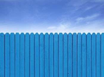 Blue wooden fence against sky