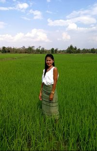 Young woman standing in farm against sky