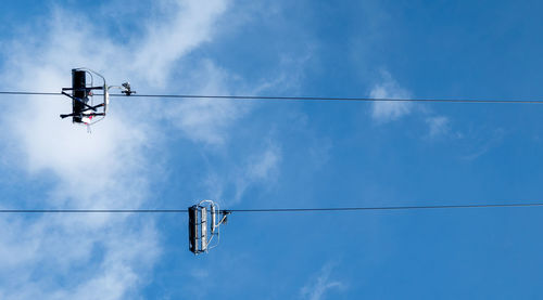 Low angle view of overhead cable cars against blue sky