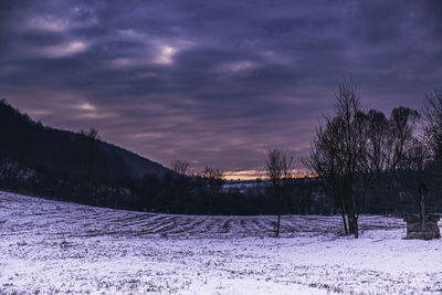 Scenic view of snow covered field against sky at sunset