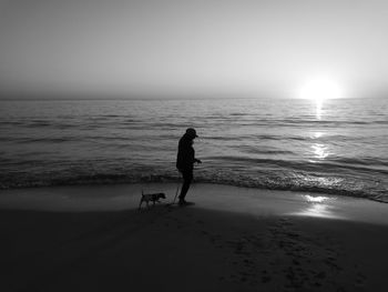 Man and dog on beach against sky