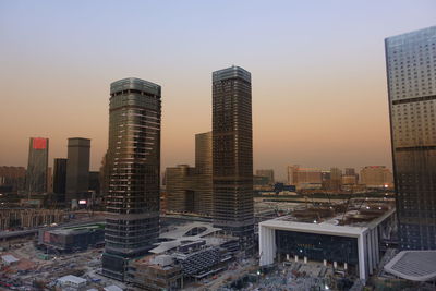 Modern buildings in city against sky during sunset