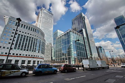 City street by modern buildings against sky