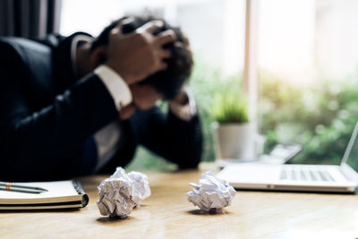 Tired man with crumpled papers sitting at desk in office