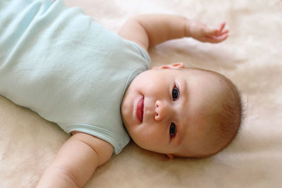 High angle portrait of cute baby girl lying on bed