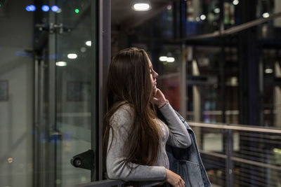 Woman looking away while standing by railing