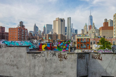 Graffiti on walls and buildings in manhattan against sky