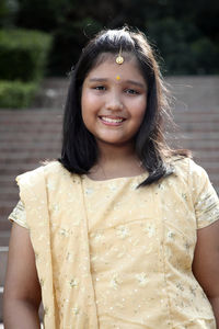 Portrait of girl smiling while standing in traditional clothing at park