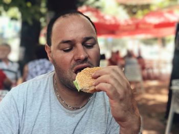 Close-up of mid adult man eating burger at sidewalk cafe