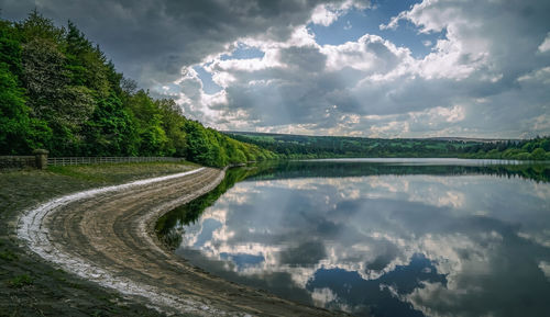 Panoramic shot of road along plants and trees against sky