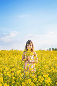 Portrait of cute girl holding flowers on field
