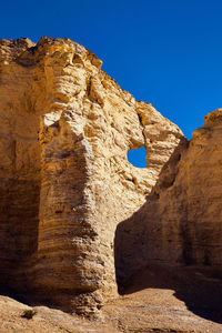 Low angle view of rock formation against clear blue sky