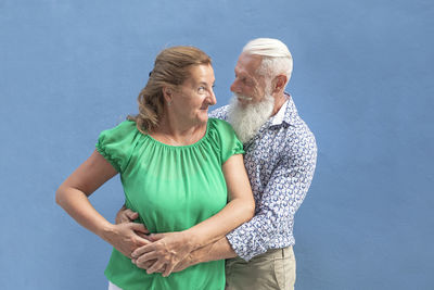 Man and woman standing against blue wall
