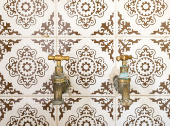 Close-up of faucets on tiled wall