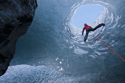 Woman climbing out of glacier cave / sólheimajökull glacier in iceland