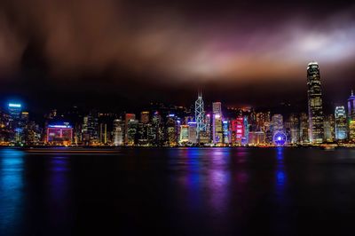  victoria harbor against modern buildings in city during night