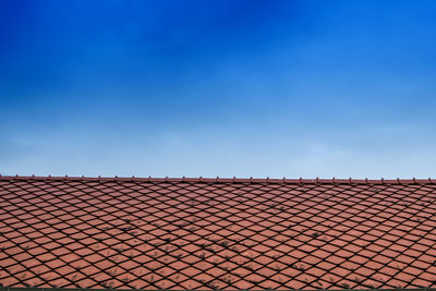 Fence on roof of building against blue sky