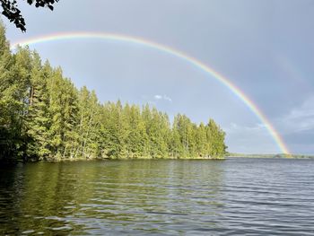 Scenic view of rainbow over trees against sky