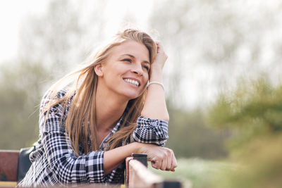 Portrait of smiling young woman against trees