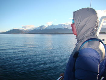 Rear view of man looking at lake against mountain range