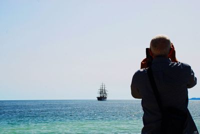 Rear view of man looking at sea against sky