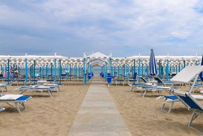 Chairs on beach against cloudy sky