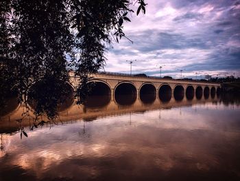 Arch bridge over river against sky