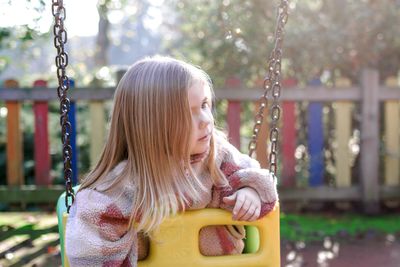 Portrait of young girl swinging at playground