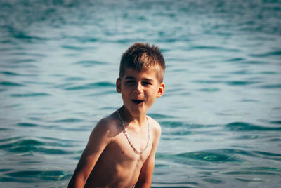 Portrait of shirtless boy with mouth open standing in sea