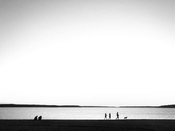 Silhouette people on beach against clear sky