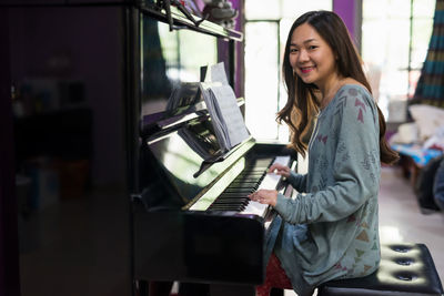 Portrait of smiling young woman playing piano