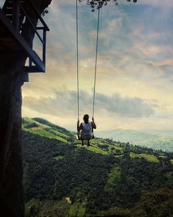 Woman photographing field against cloudy sky