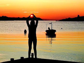 Silhouette man standing by sea against sky during sunset