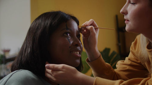 Side view of young woman applying make-up