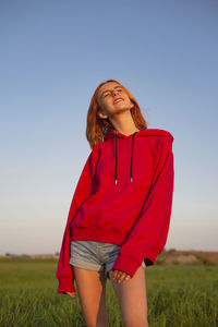 Young woman standing on field against clear sky