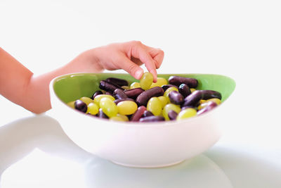 Close-up of hand holding fruits in bowl