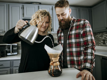 Smiling young couple make coffee in morning in their kitchen