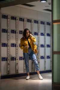 Young woman standing against lockers