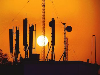 Silhouette cranes against orange sky