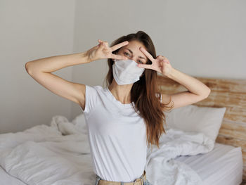 Young woman sitting on bed at home