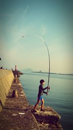 Side view of boy casting fishing line in sea