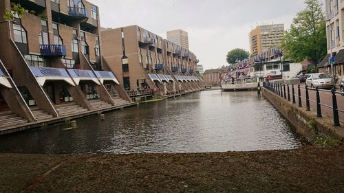 Canal amidst buildings against sky in city