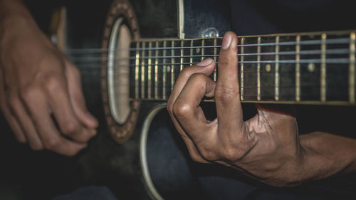 Midsection of man playing guitar