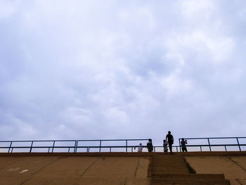 People on railing against sky