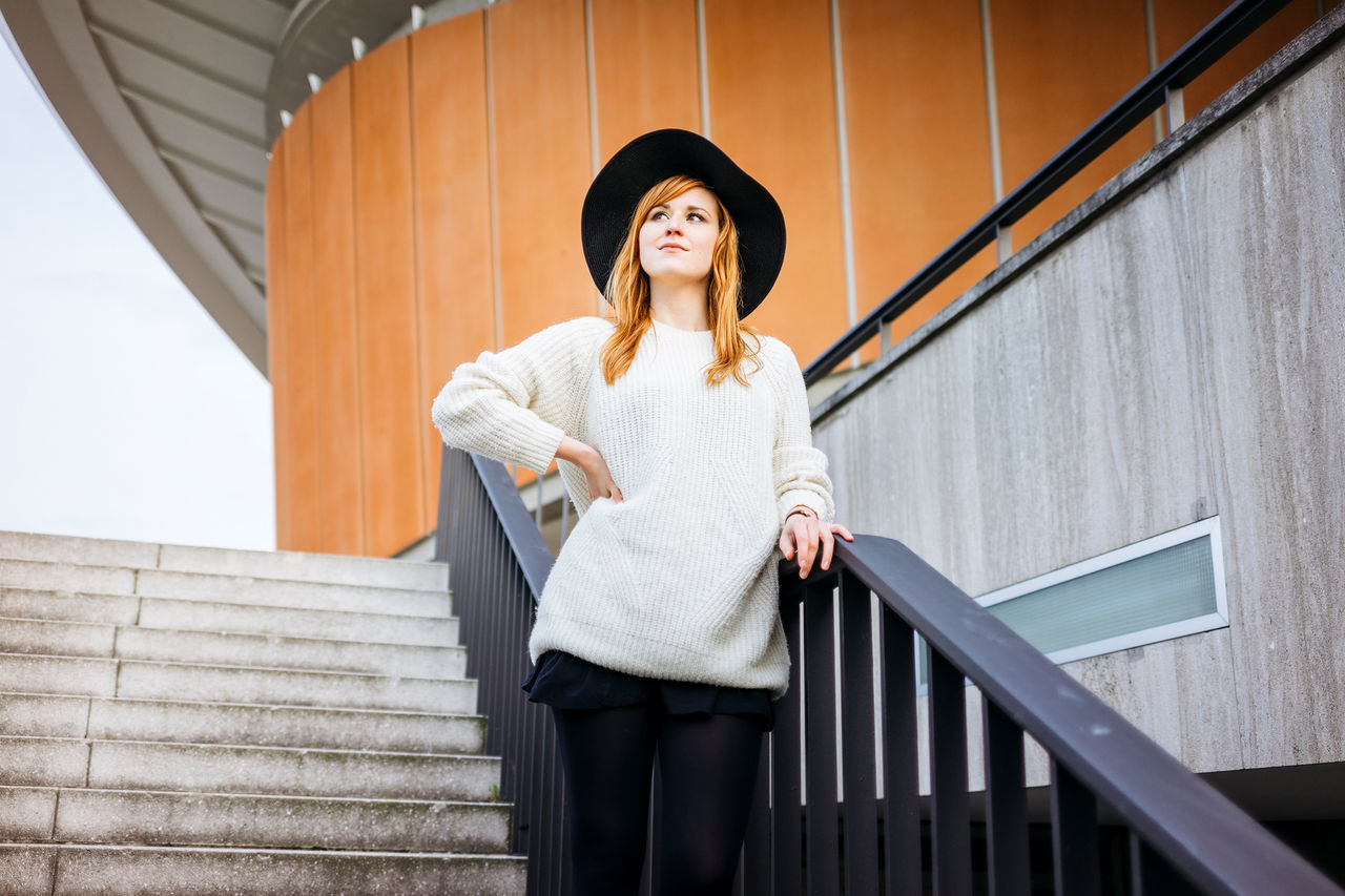 architecture, staircase, railing, one person, steps and staircases, front view, real people, built structure, standing, young women, lifestyles, young adult, women, adult, casual clothing, three quarter length, day, looking away, leisure activity, outdoors, beautiful woman, hairstyle