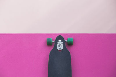 High angle view of skateboard on pink table against wall