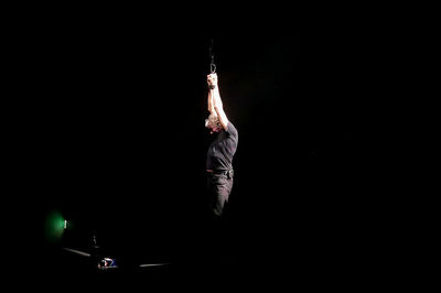 Midsection of man dancing against black background