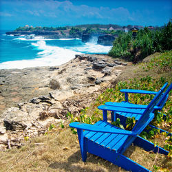 Chairs on beach against blue sky