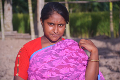 Portrait of woman holding pink while standing outdoors