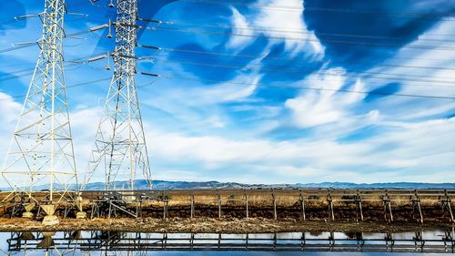 Low angle view of electricity pylon against blue sky